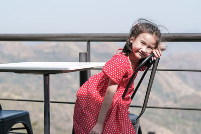 Girl standing by railing against sky