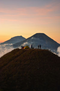 People on mountain against sky during sunset