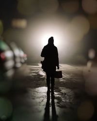 Rear view of silhouette man walking in water at night