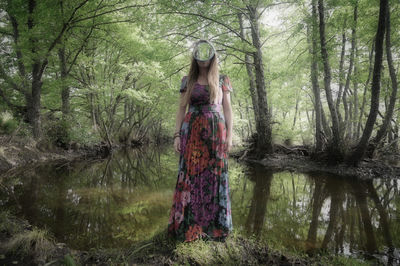 Woman standing by tree in forest