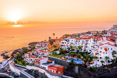 High angle view of townscape by sea during sunset