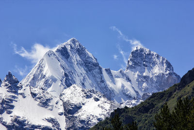 Low angle view of snow mountains against blue sky