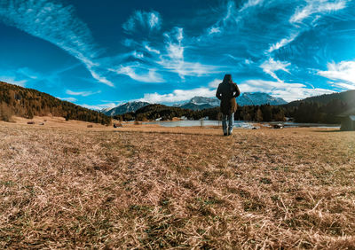 Rear view of man on field against sky