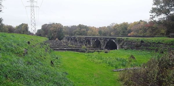 Arch bridge on field against sky