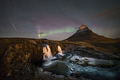 Scenic view of waterfall against sky at night