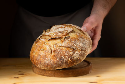 Midsection of man holding bread on table