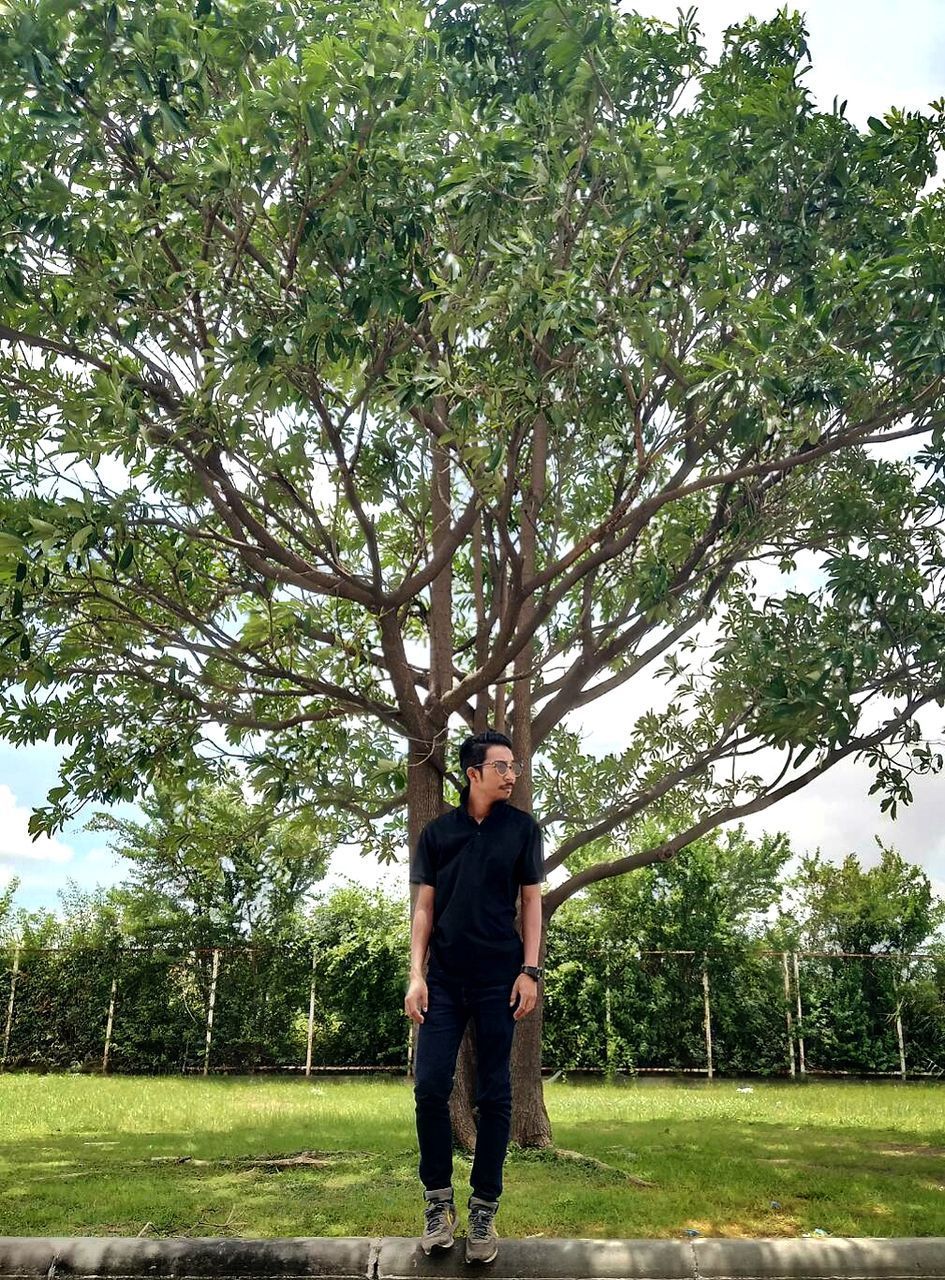 PORTRAIT OF YOUNG MAN STANDING IN PARK