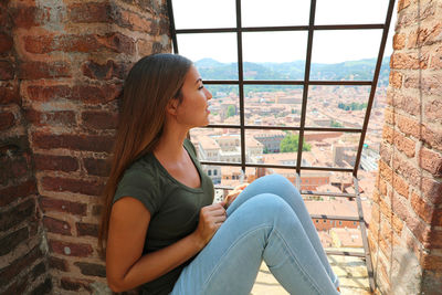 Side view of young woman looking through window
