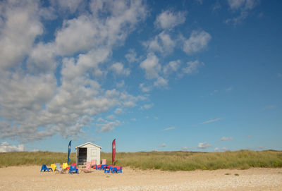 Wooden hut and chairs on a sandy beach with a beautiful blue sky