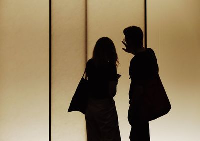 Silhouette friends standing against wall