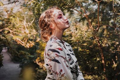 Side view of woman standing against plants