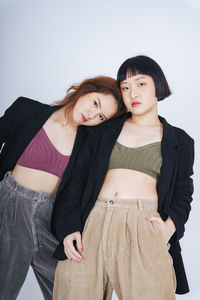 Portrait of lesbian couple wearing blazer against gray background