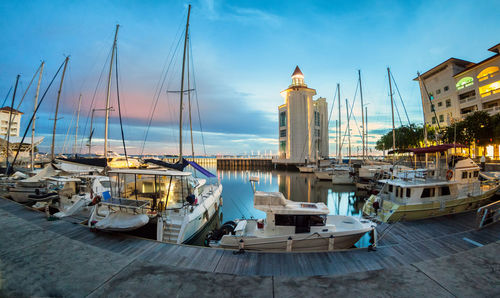 Sailboats moored at harbor against sky