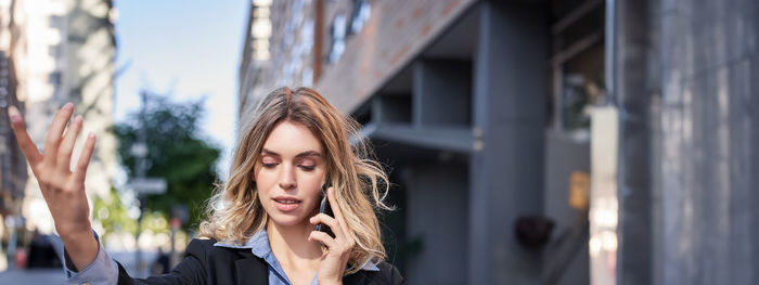 Portrait of young woman standing against building