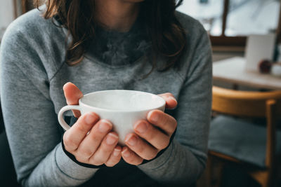 Midsection of woman drinking coffee