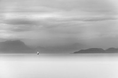 Boat sailing on sea against mountain and sky