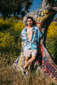 Portrait of man leaning on tree trunk