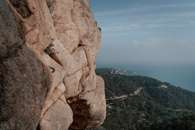 Scenic view of rock formation with climbing hooks by sea against sky