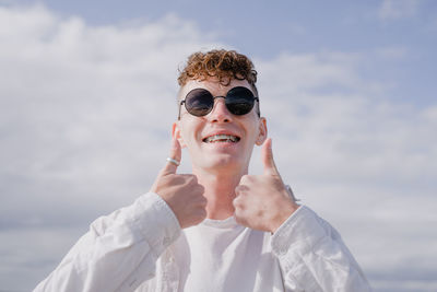 Young woman wearing sunglasses while standing against sky