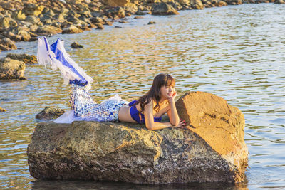 Full length of woman sitting on rock