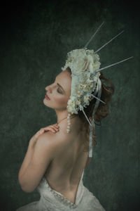 Rear view of female model wearing headdress against wall