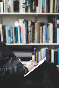 Midsection of therapist with book sitting at home office