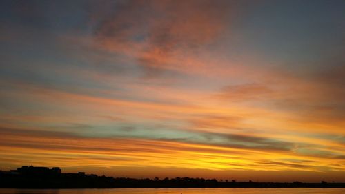 Scenic view of silhouette field against orange sky