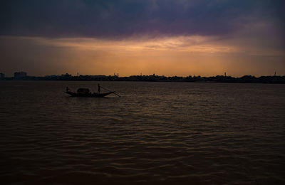 Silhouette boat in sea against sky during sunset