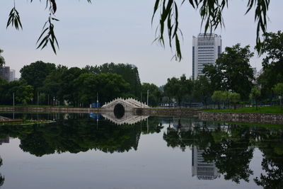 Reflection of bridge and trees on lake against sky
