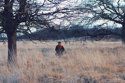 Mid adult woman standing amidst grassy field