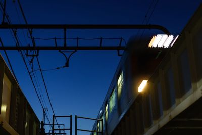 Blur image of illuminated train on bridge against clear blue sky at dusk