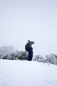Rear view of man standing on snow covered landscape
