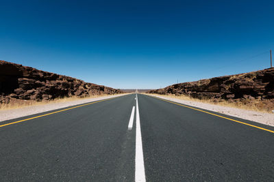 Empty road against clear blue sky