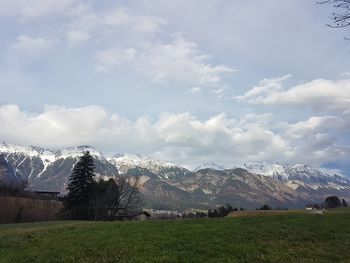 Scenic view of field by snowcapped mountains against sky