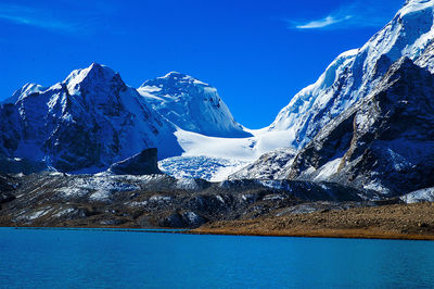 Scenic view of snowcapped mountains against blue sky