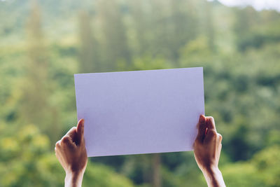 Midsection of person holding paper against blurred background