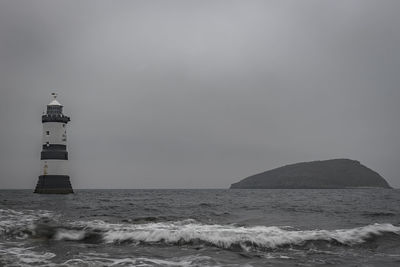 Lighthouse by sea against sky