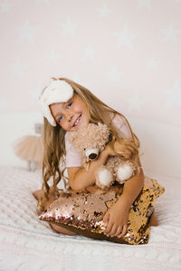 Cute little girl hugging a teddy bear is lying on a cozy bed, a happy little baby