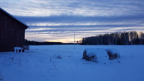 Scenic view of snow covered field against sky during sunset