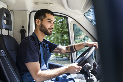 Side view of confident young male owner driving food truck in city