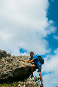 Low angle view of man on rock against sky