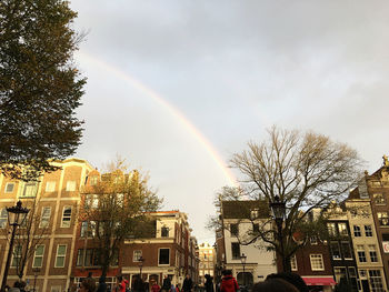 Low angle view of rainbow over buildings in city against sky