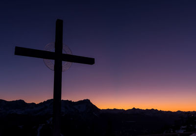 Silhouette cross against sky during sunset