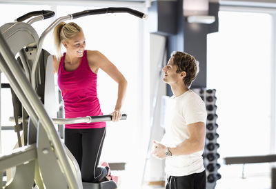 Instructor talking to customer exercising at gym