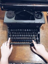 Cropped hands typing on typewriter over table