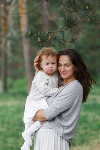 Portrait of happy girl with children standing against plants