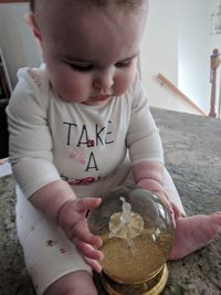 Close-up of baby girl playing with snow globe at home