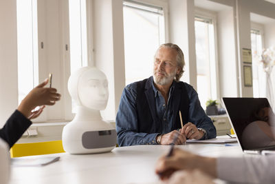 Business people discussing robot voice assistant during meeting