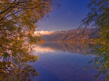 Scenic view of lake against sky at sunset