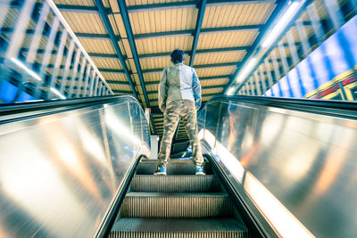 Rear view of man standing on escalator